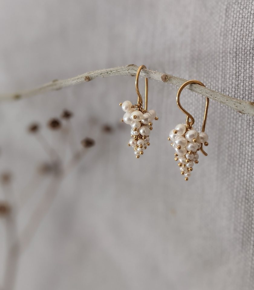 A pair of pearl earrings by Kate Wood Jewellery hanging from a twig