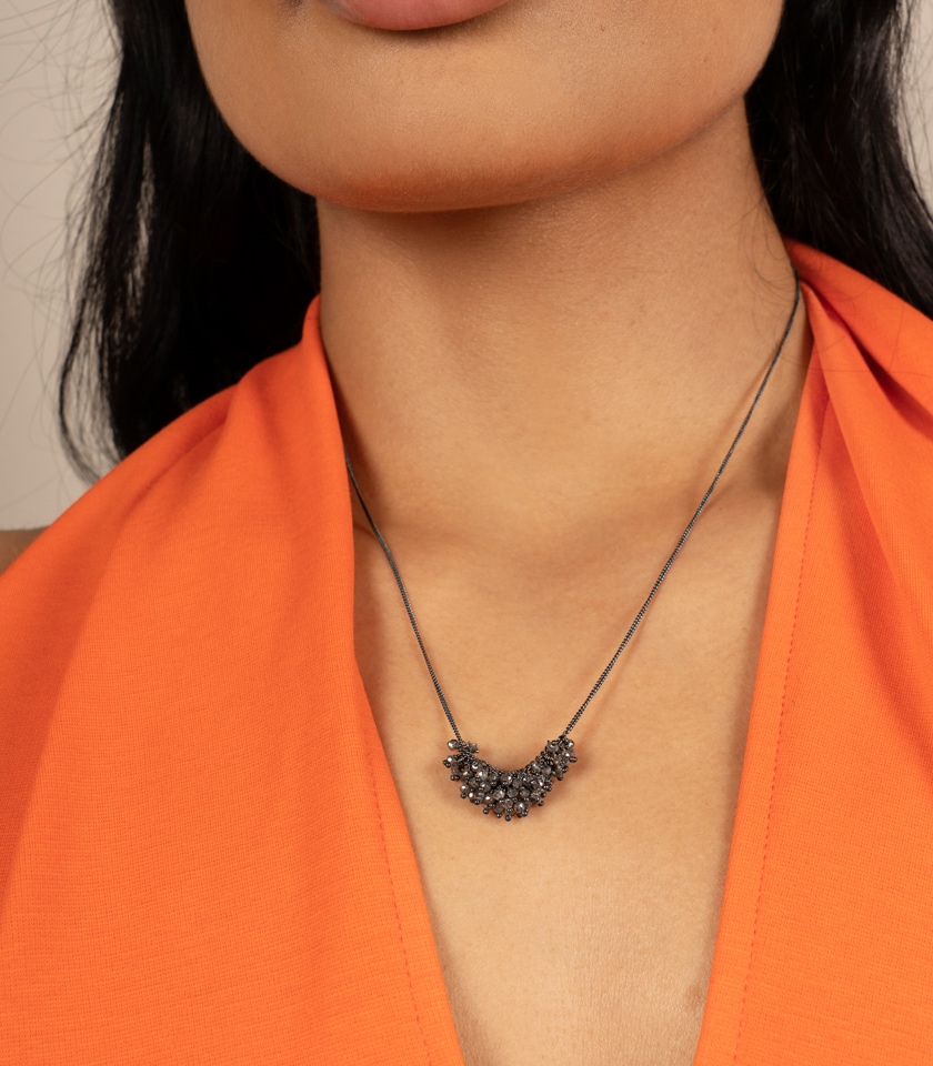 Necklace of grey diamonds and oxidised silver worn by a model in an orange top