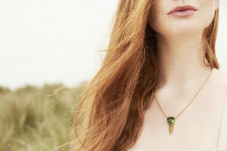 Photo of model wearing emerald pendant necklace.