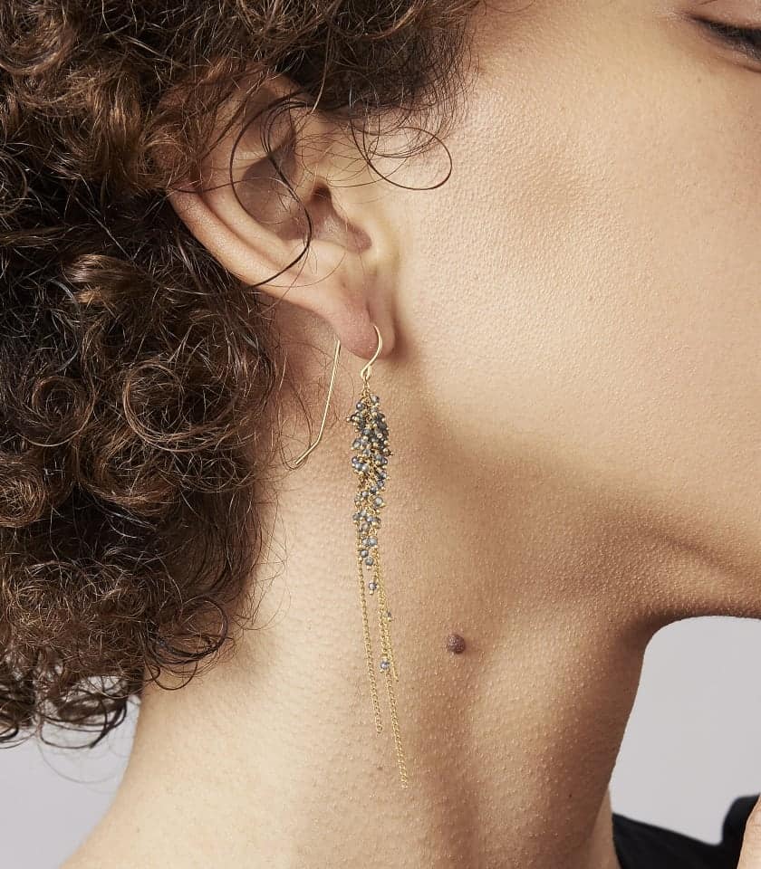 Photo of model wearing sapphire and gold earrings.