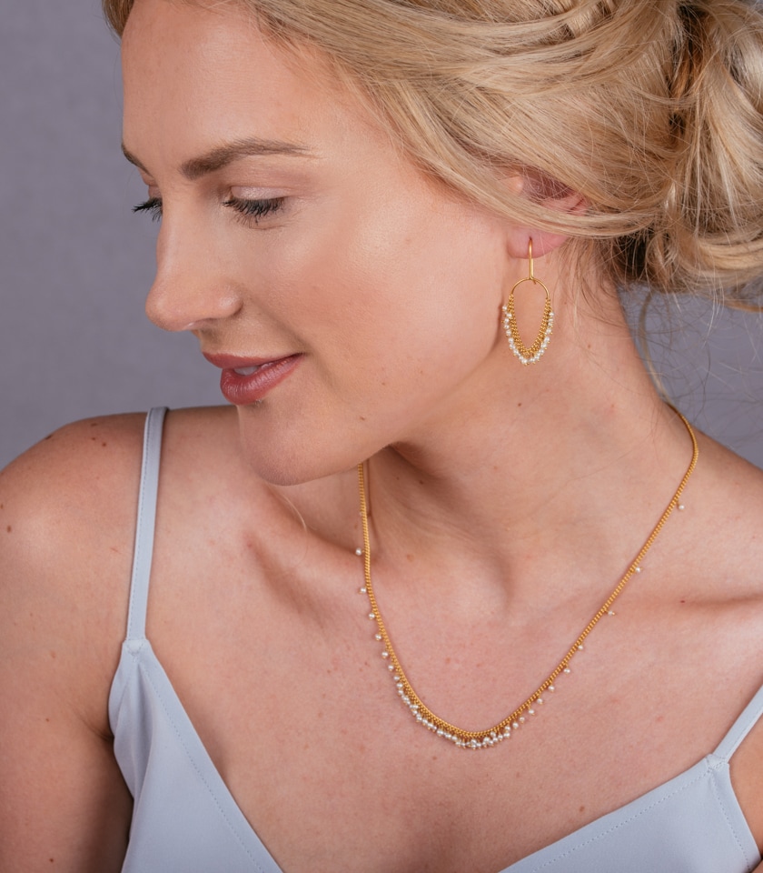 Photo of model wearing a pearl and gold neckalce