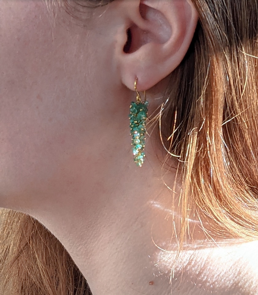 Photo of model wearing green emerald drop earrings
