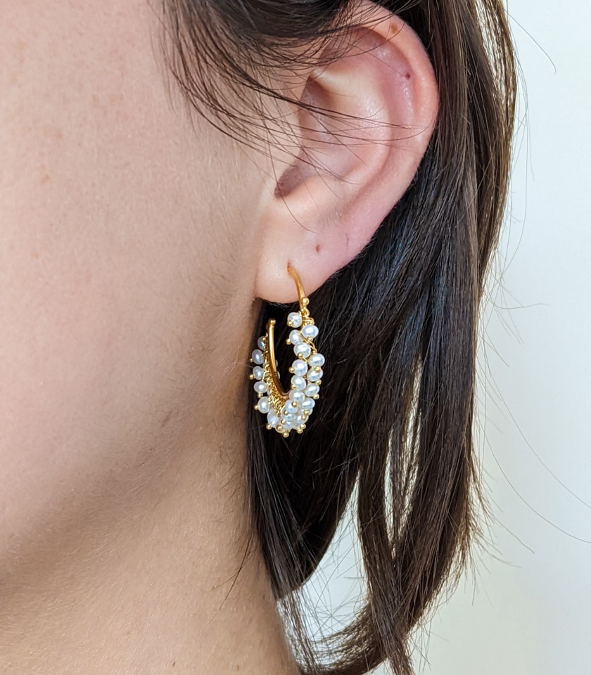 Gold vermeil and pearl hoop earrings worn by a model