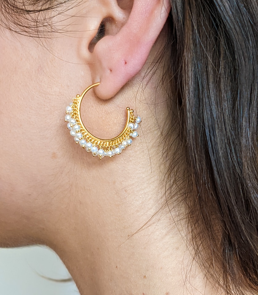 Photo of a model wearing gold and pearl hoop earrings