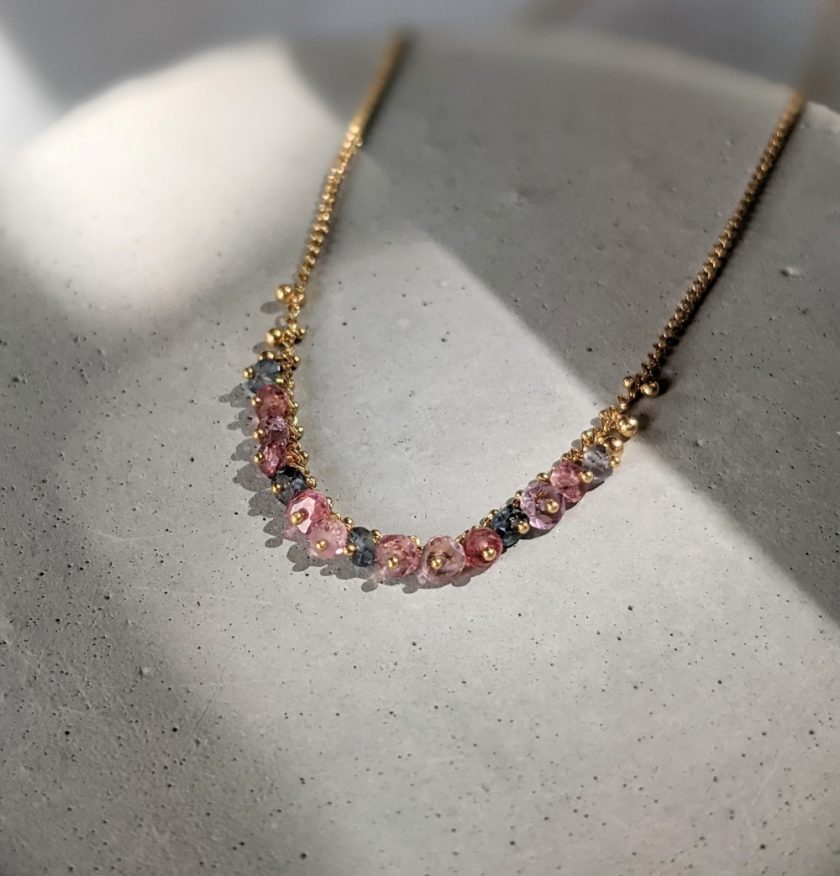 Pinned necklace in spinel and gold vermeil by Kate Wood Jewellery on a concrete background
