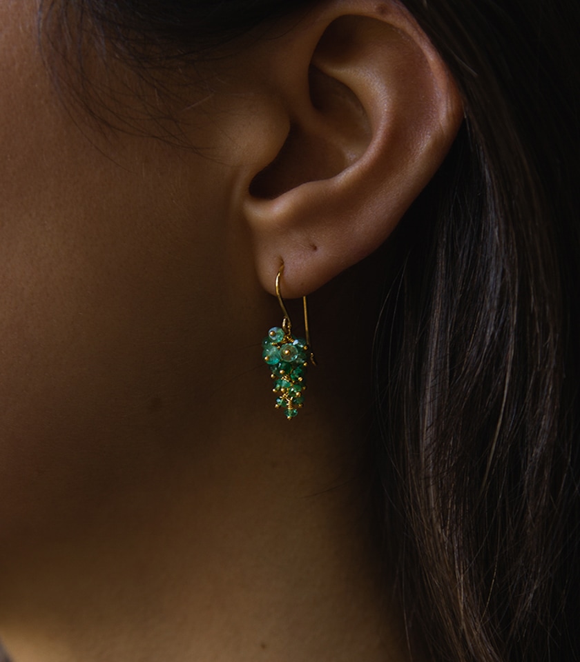 Close up of a model wearing green emerald grape earrings