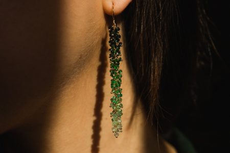 Model wearing long emerald drop earrings