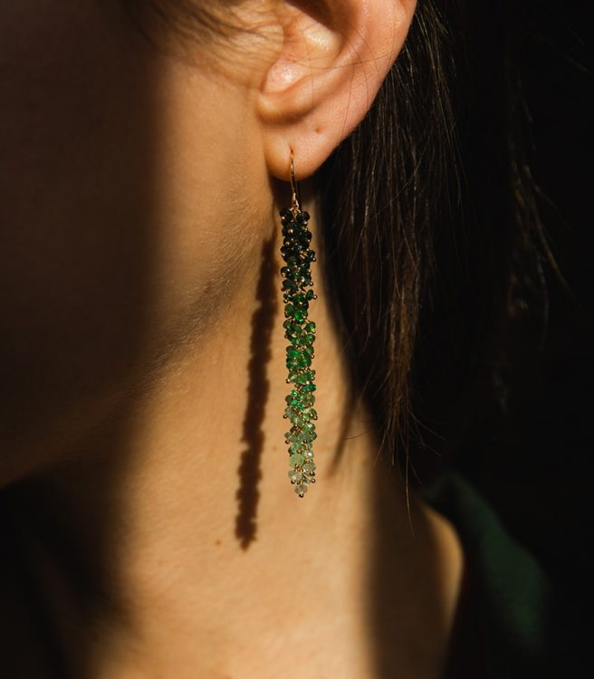 Model wearing long emerald drop earrings