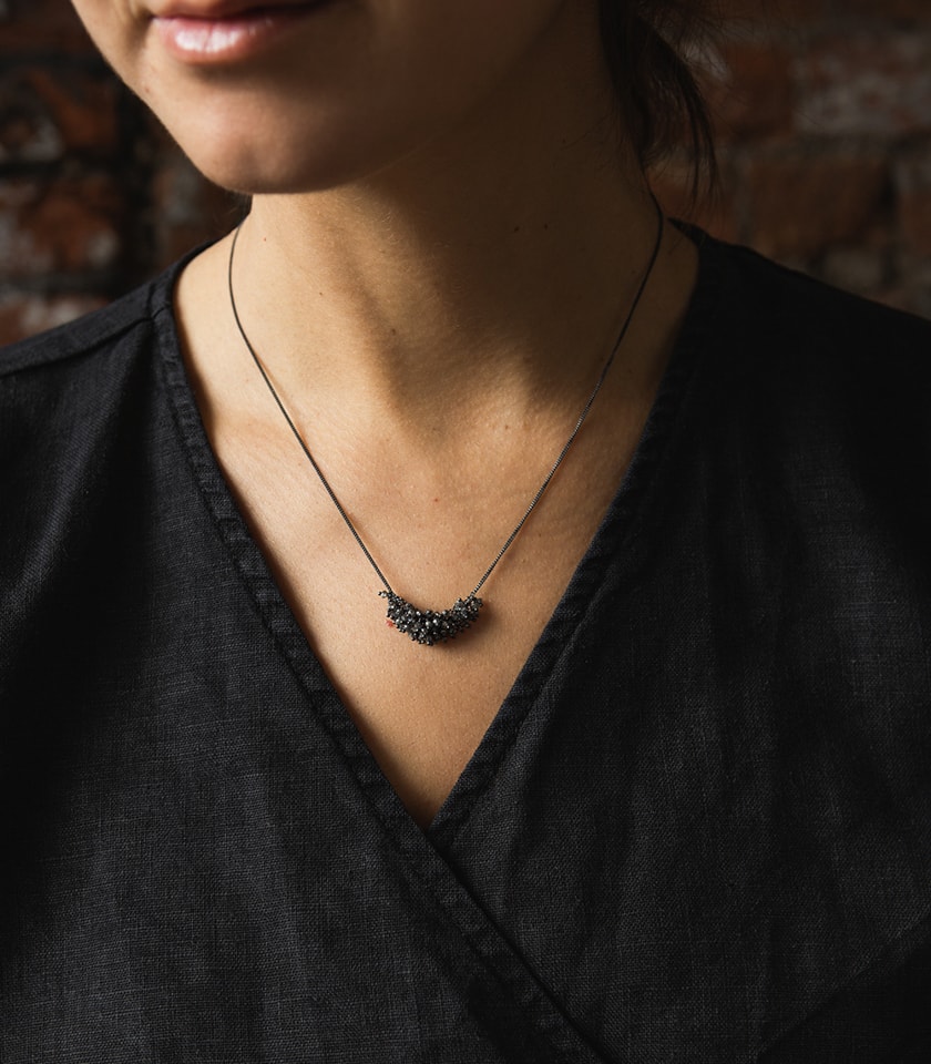 Necklace with grey diamonds on silver chain worn by a model in a black top