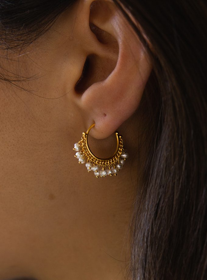 A model's ear wearing a pearl and gold plated silver hoop earring