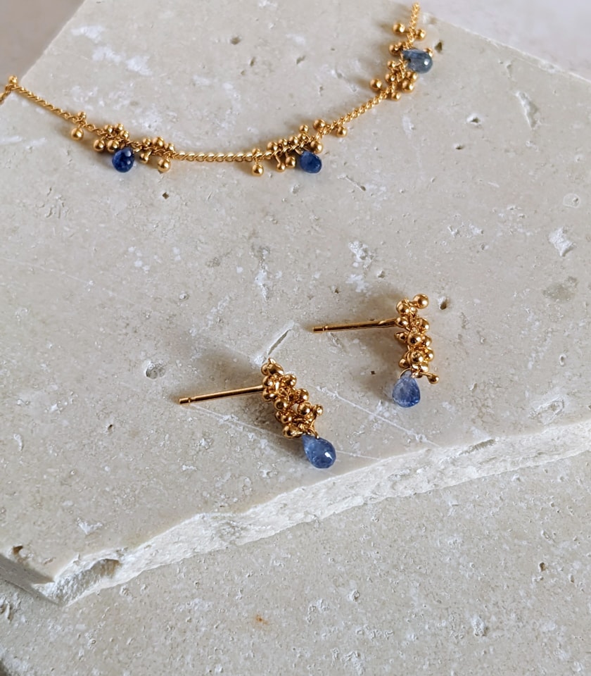 Sapphire teardop stud earrings and bracelet by a Bristol jeweller on a stone background.
